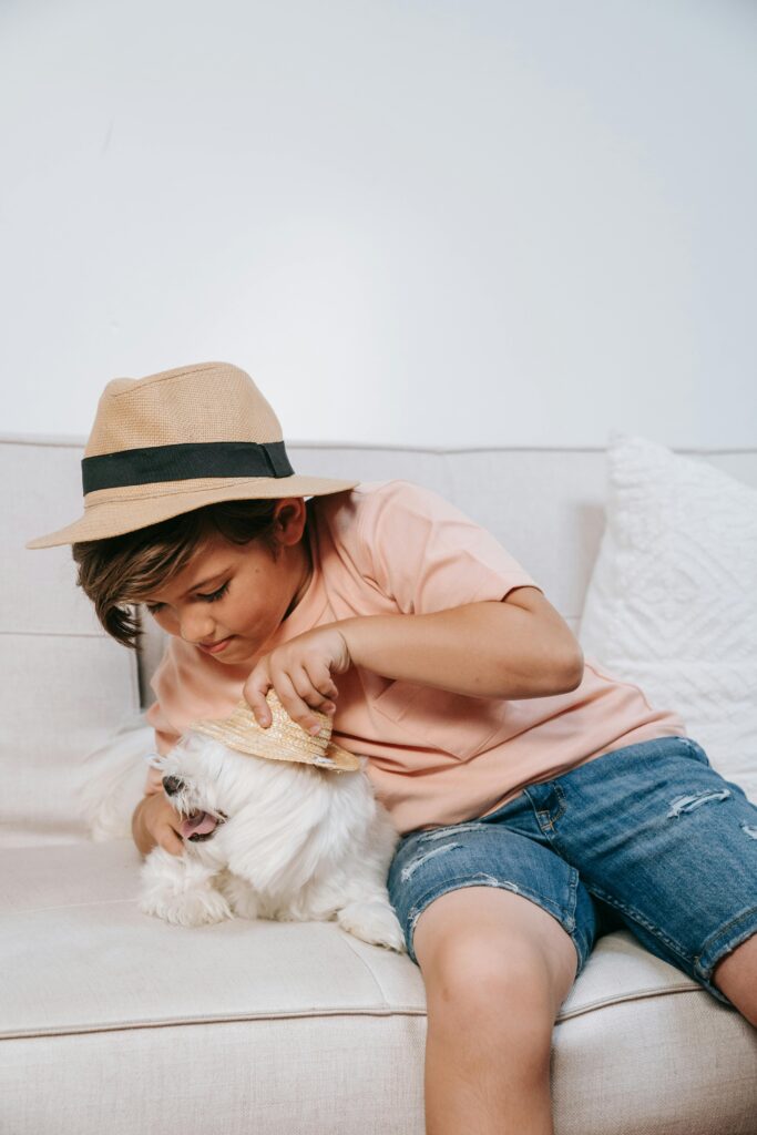 boy in hat dressing cute dog with a hat